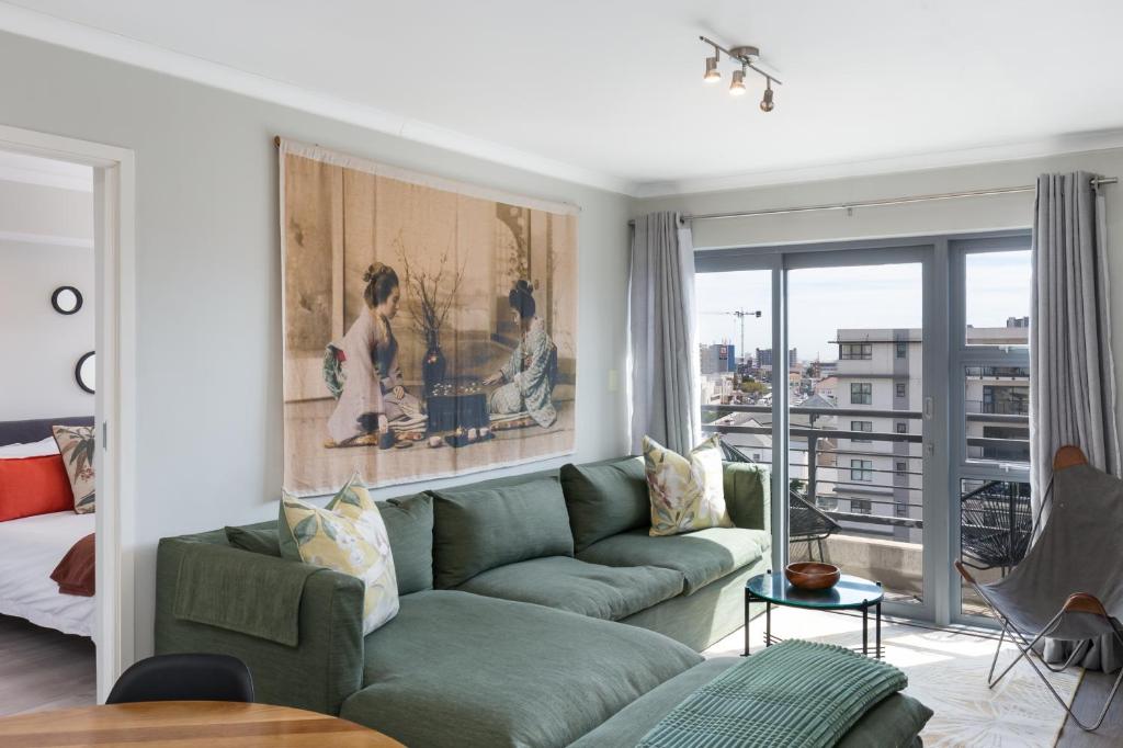 a living room with a green couch and a balcony at The Paragon Cosmo Sanctuary Sophisticated Mountain & City Views in Cape Town