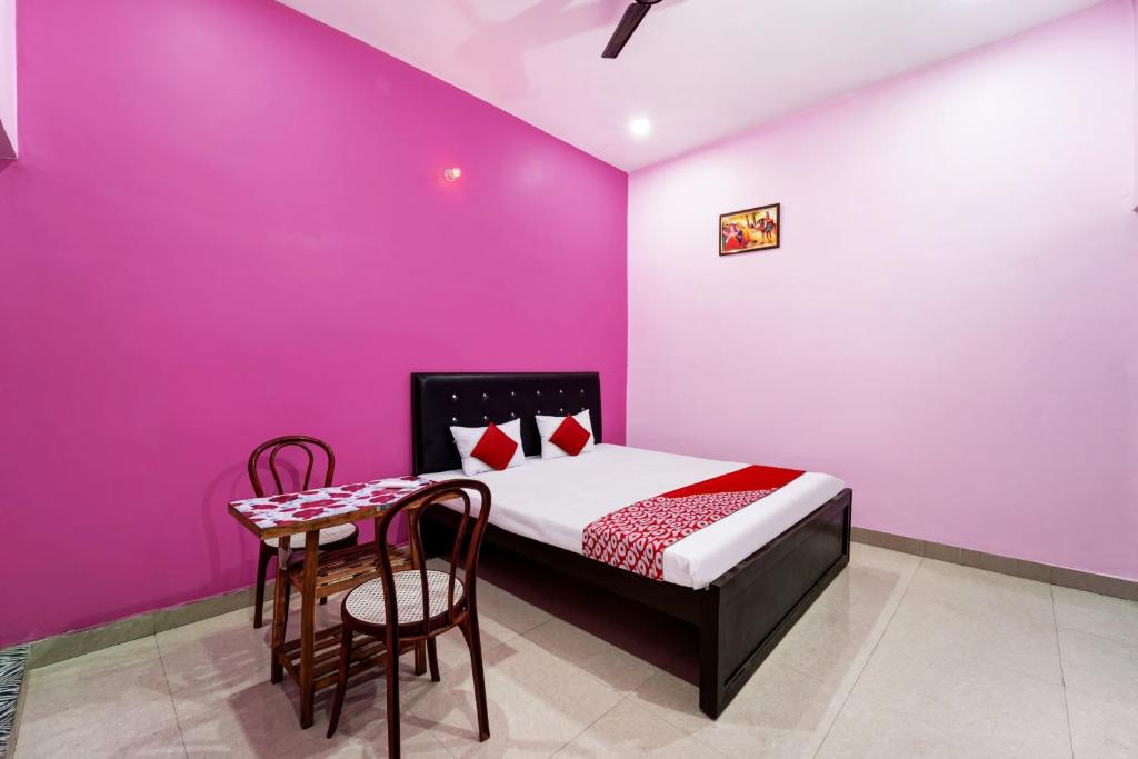 Habitación con cama, mesa y sillas. en OYO Flagship Raj Munmun Hotel, en Dhanbād