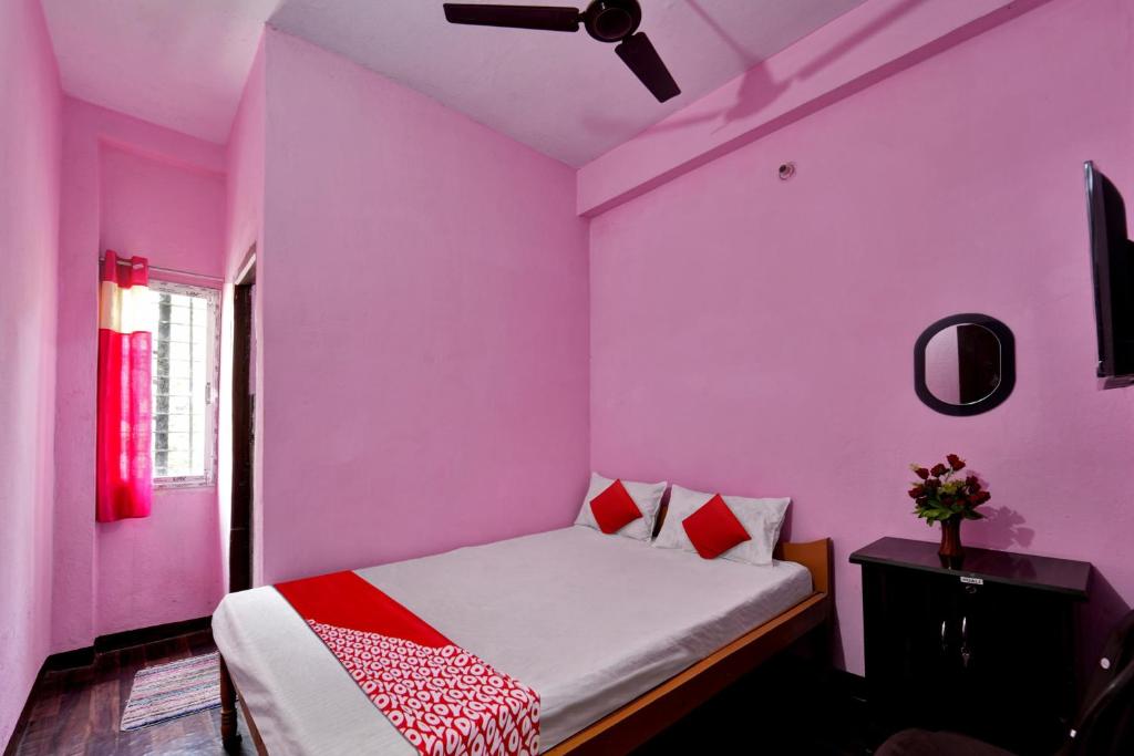 a bedroom with pink walls and a bed with red pillows at SPOT ON Hotel Gajraj in Patna