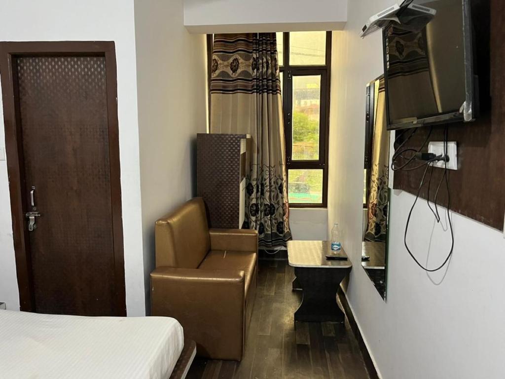 a bedroom with a bed and a chair and a television at Hotel Lords Paradise , Katra in Katra