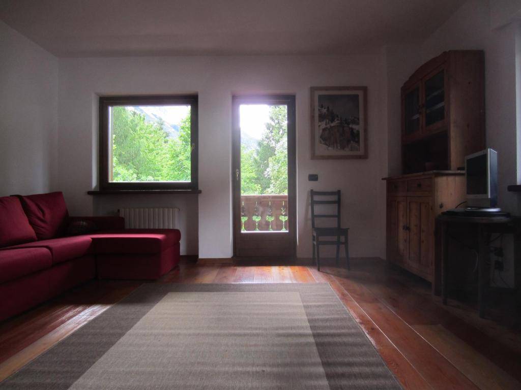 un soggiorno con divano rosso e 2 finestre di Villa Cleila Verde B a San Vito di Cadore