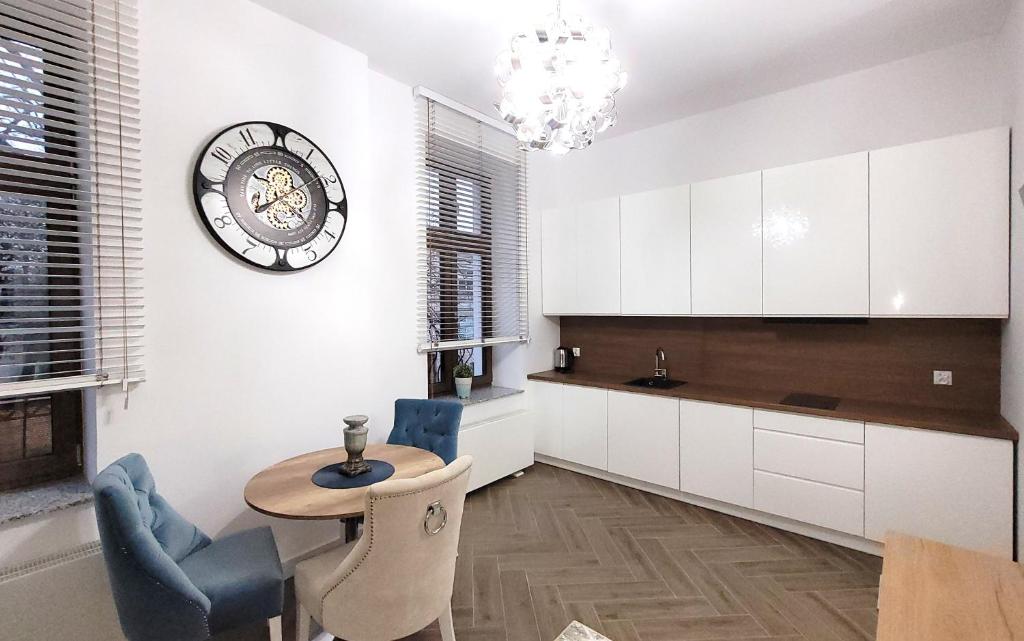 a kitchen with a table and a clock on the wall at Apartament Jaracza 28 nr 6 in Słupsk