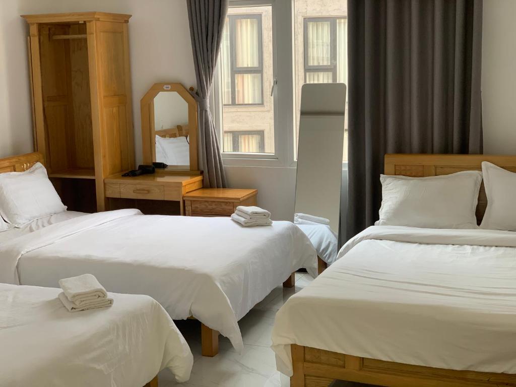 ein Hotelzimmer mit zwei Betten und einem Spiegel in der Unterkunft ThiênBảo Hotel in Da Lat