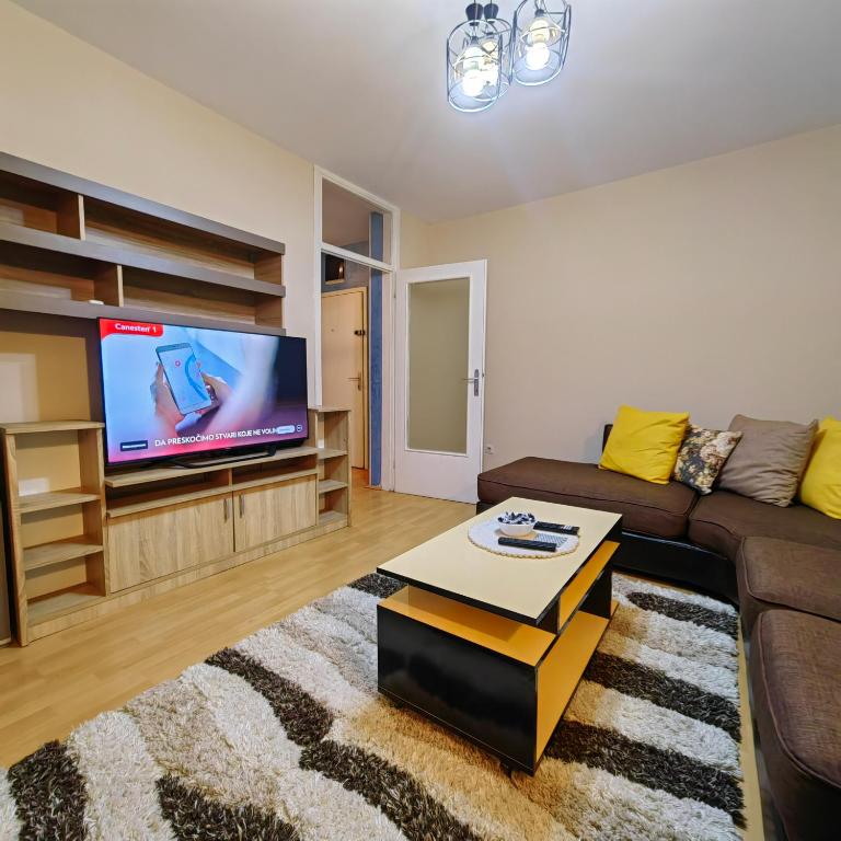 een woonkamer met een bank en een flatscreen-tv bij stan na dan centar s in Šabac