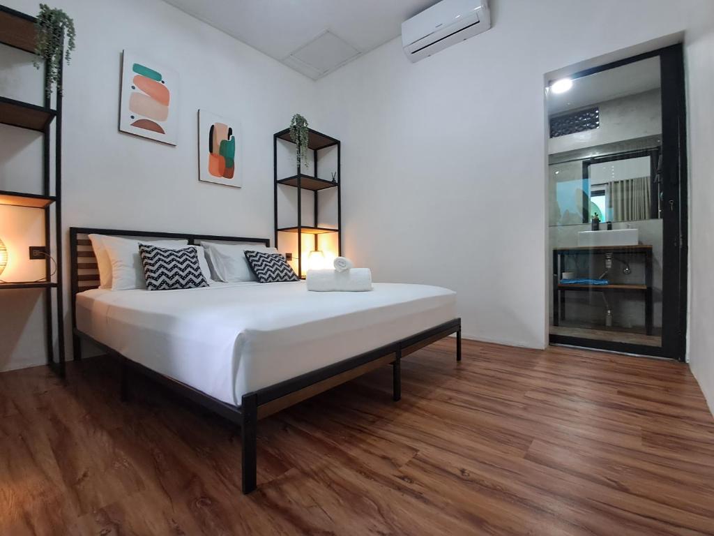 a bedroom with a large white bed and wooden floors at Las casitas de Canggu in Canggu