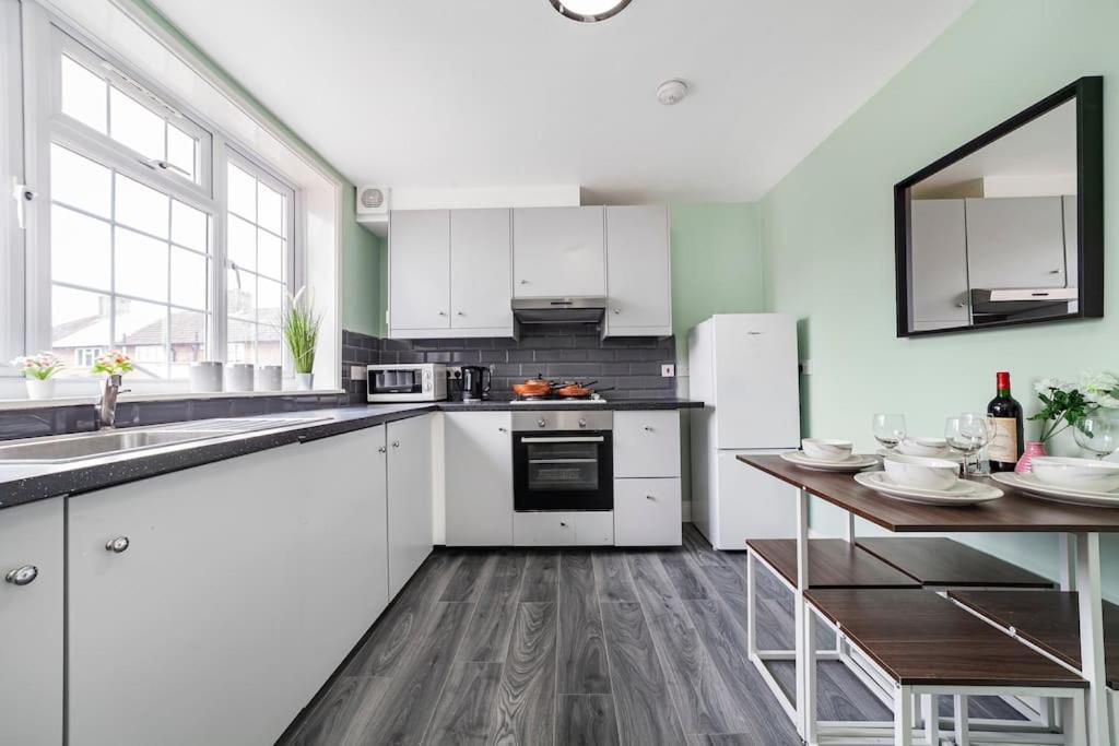 a kitchen with white appliances and a wooden table at Lovely 3-bedroom 2 bath duplex flat in SE London in Chislehurst