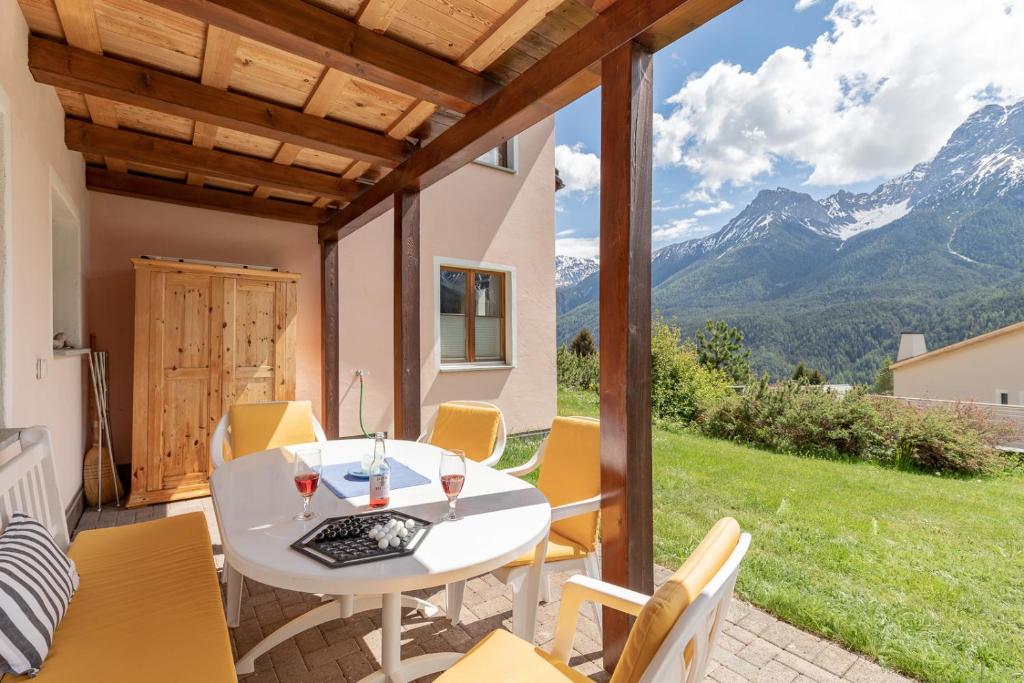 un patio con una mesa blanca, sillas y montañas en Chasa Val 735, en Scuol