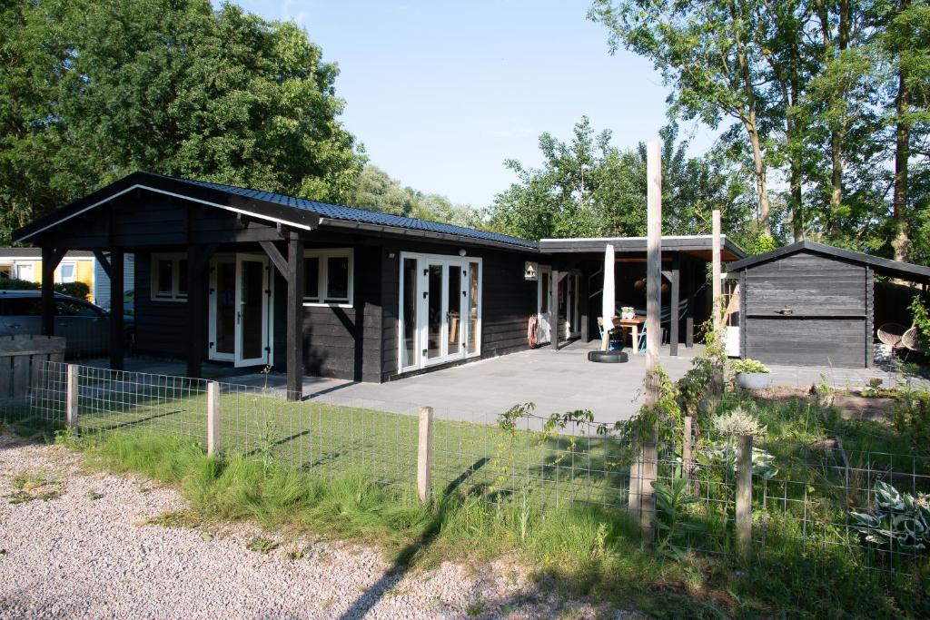 a black house with a porch and a yard at Luxe en ruim chalet met airco bij Leekstermeer in Matsloot