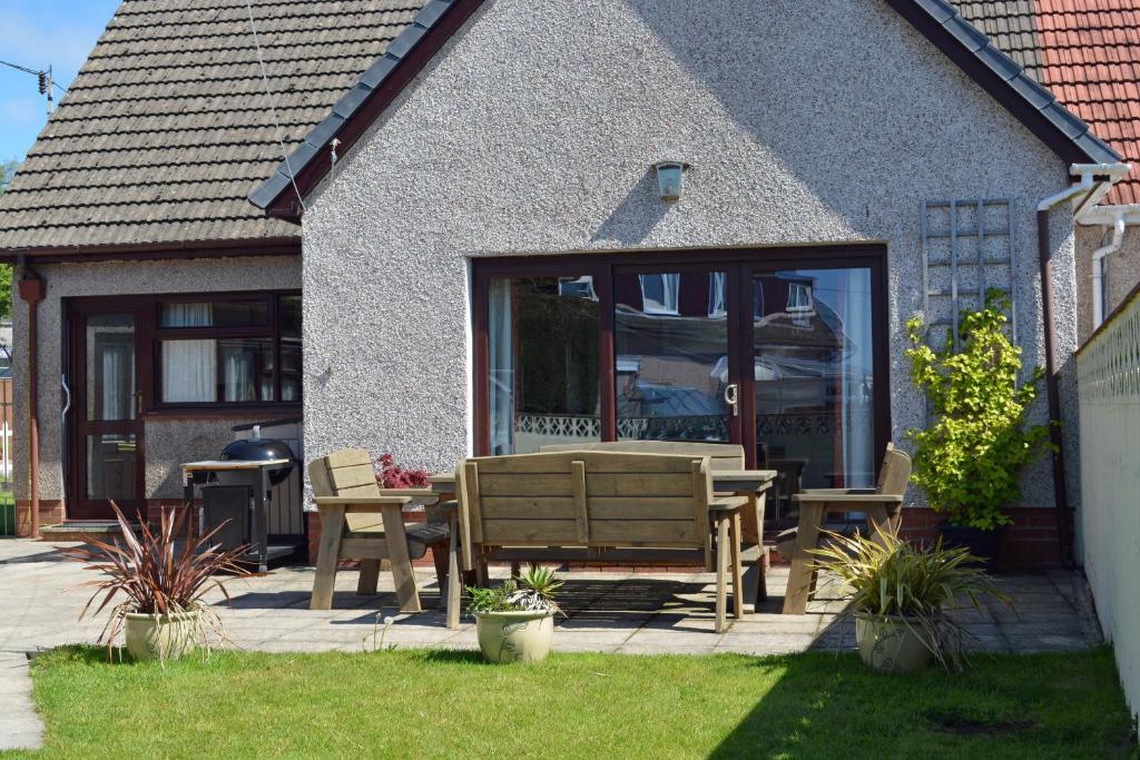 un patio con mesa y sillas frente a una casa en Driftwood Kilgetty, en Begelly