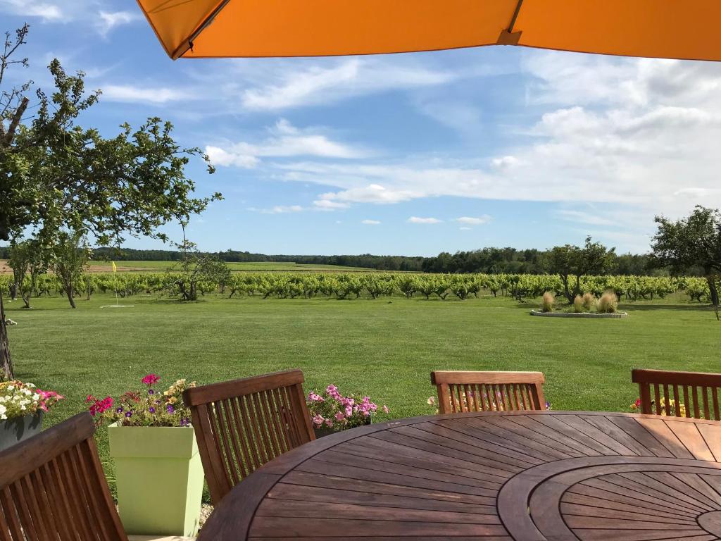 een houten tafel met stoelen en uitzicht op een veld bij Le Chainous in Pouillé