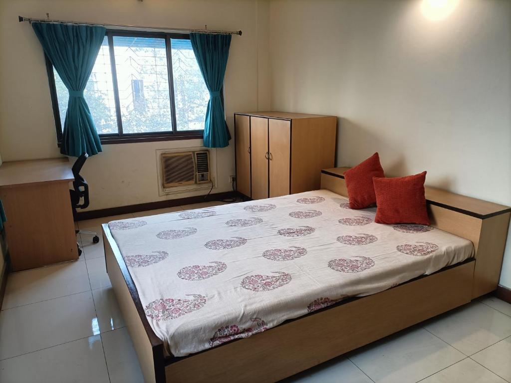 Un dormitorio con una cama con almohadas rojas. en Nestled in heart of the city en Calcuta