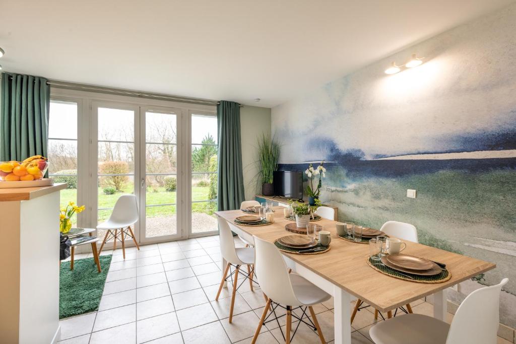 a dining room with a table and white chairs at Belle Dune in Fort-Mahon-Plage