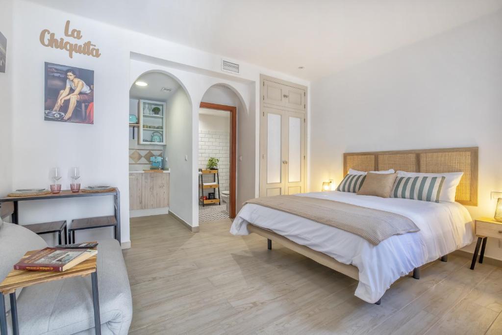 a white bedroom with a large bed and a table at El rincón de la Chiquita & Parking in Córdoba
