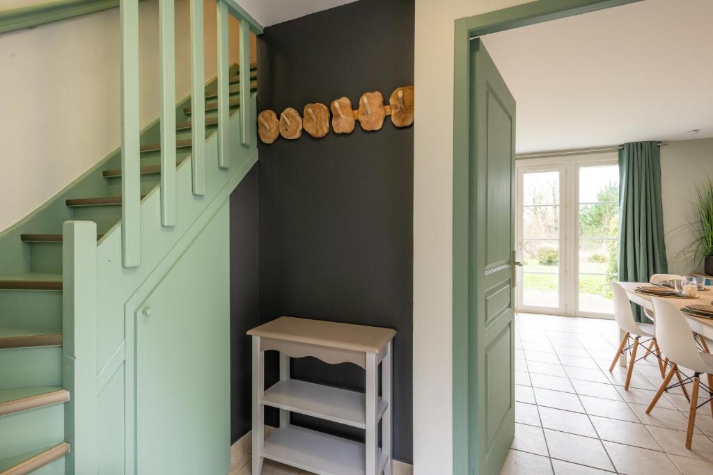 a hallway with a green staircase with a table and chairs at Belle Dune in Fort-Mahon-Plage