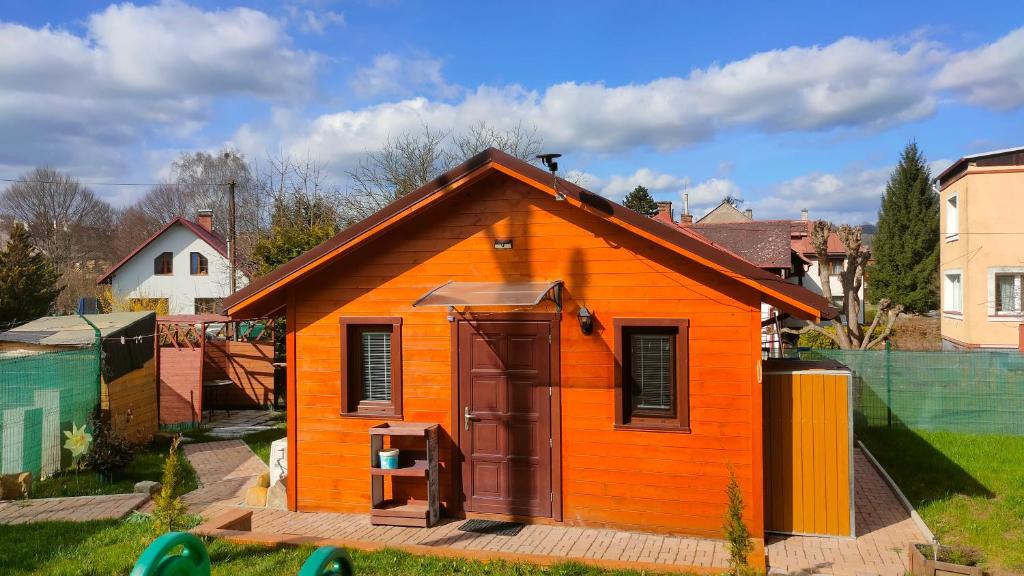una pequeña casa naranja con una puerta en un patio en Tiny Treperka, en Semily