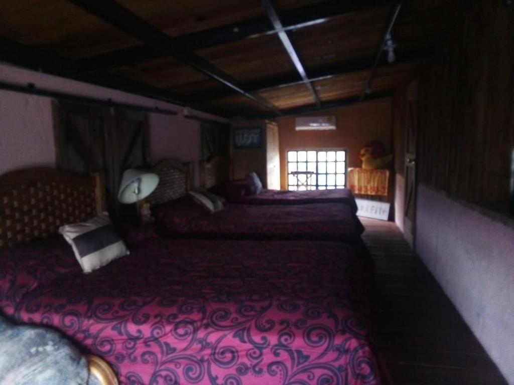 a bedroom with three beds and a window at QUINTA CARLOTITA in Barranca