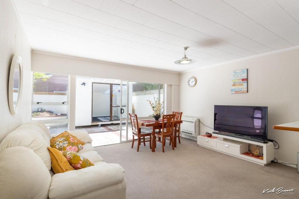 a living room with a couch and a tv and a table at 5 bedroom modern house, private spacious backyard in Lower Hutt