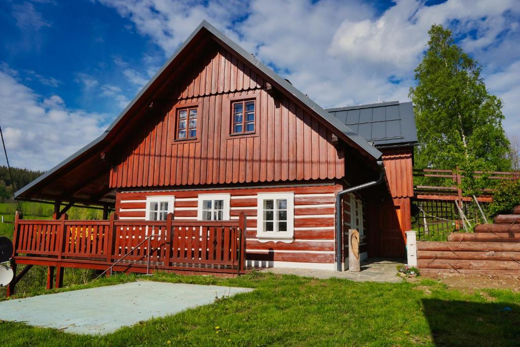 une petite maison rouge avec une terrasse en bois dans l'établissement Chata Říp, à Rokytnice nad Jizerou