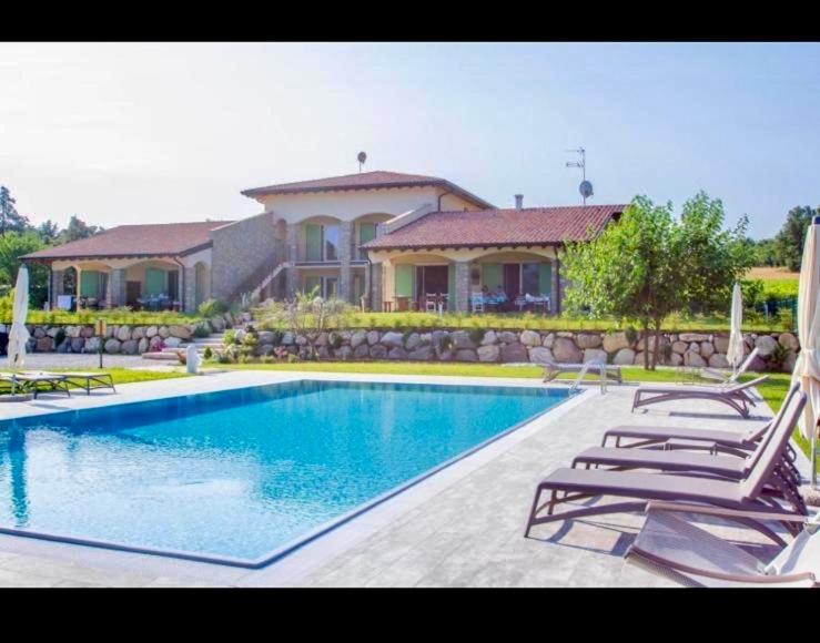 ein Pool mit zwei Gartenstühlen und ein Haus in der Unterkunft Orchidea Del Garda in Peschiera del Garda