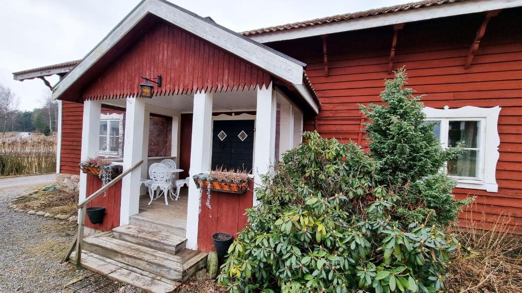 Large house, Baggetorp, close to swimming and fishing in Nykoping في نيكوبينغ: منزل احمر وباب احمر وشرفة
