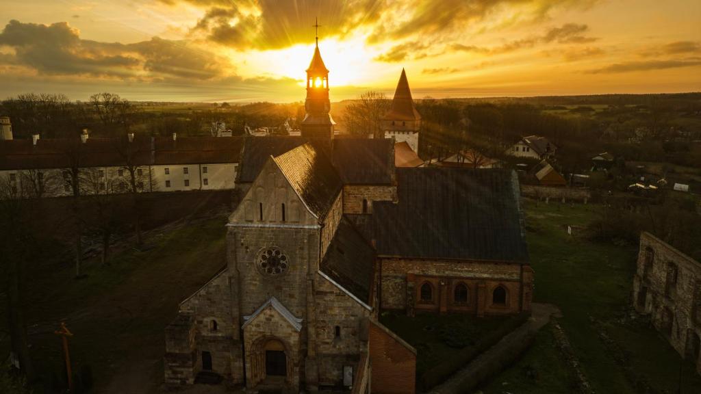 Hotel Podklasztorze في سولييوف: كنيسة قديمة مع برج الساعة عند غروب الشمس