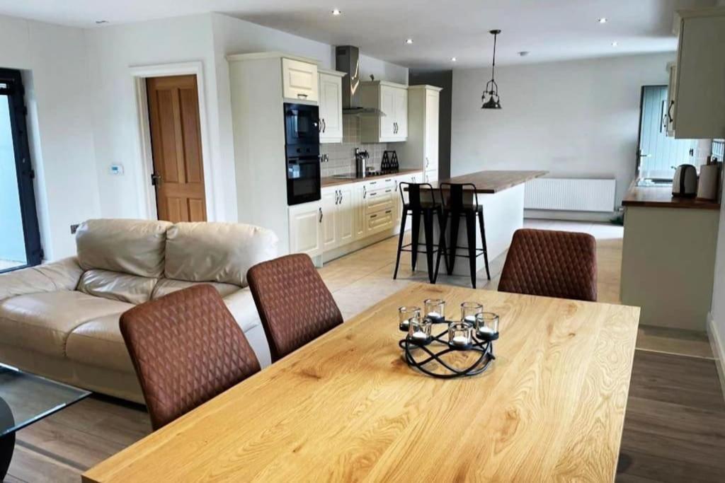 a living room and kitchen with a table and a couch at Aghadoe Millers - Modern 3 bed house Killarney in Fossa