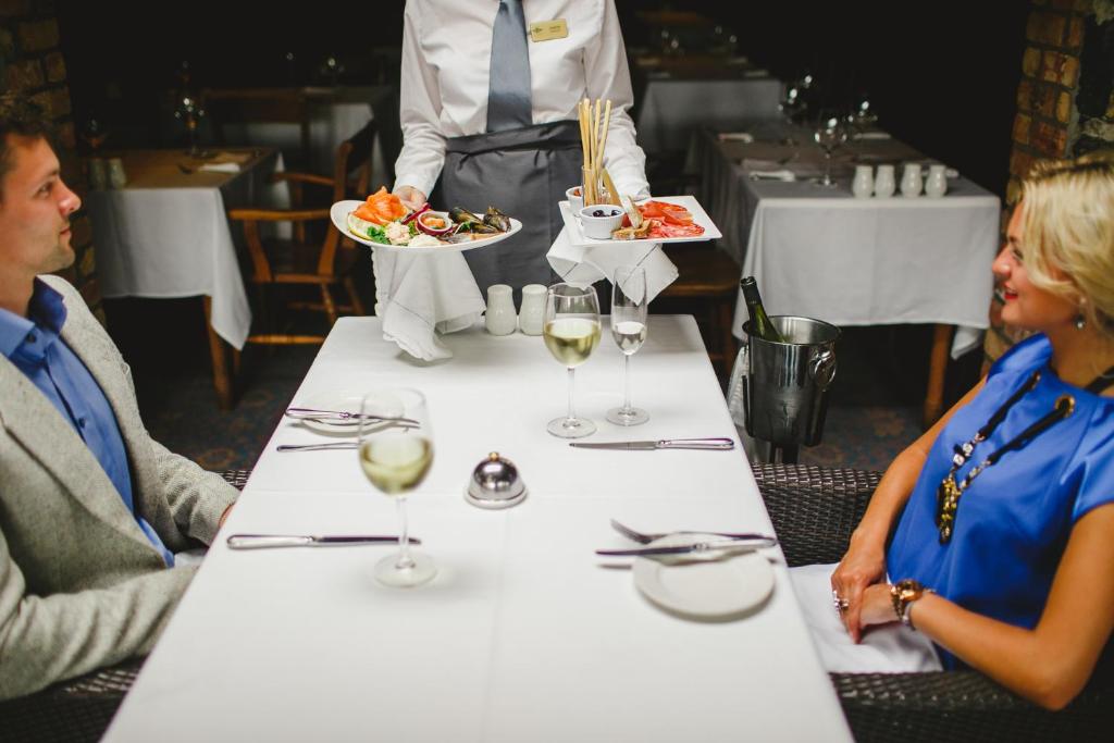 a man and woman sitting at a table with wine glasses at Bushmills Inn Hotel & Restaurant in Bushmills