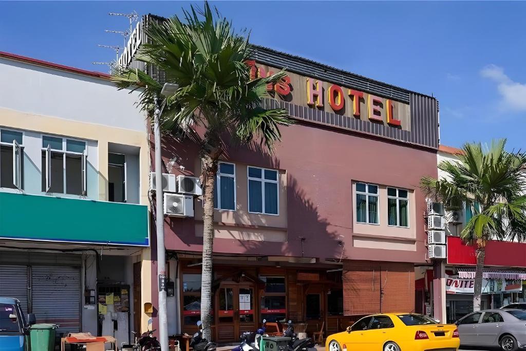 un hotel en una calle de la ciudad con una palmera en Fins Hotel en Alor Setar