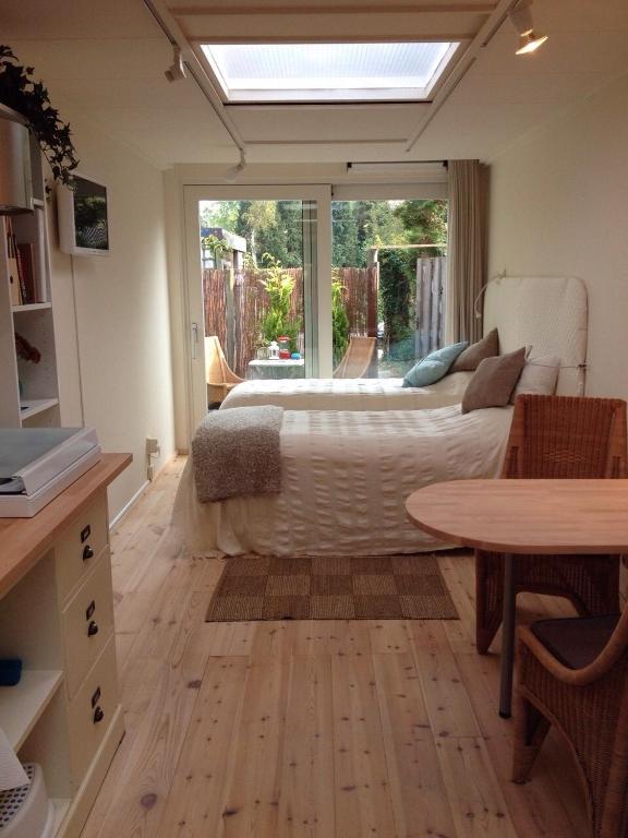 a bedroom with a bed and a table and a window at BBBoekelo appartement in Boekelo