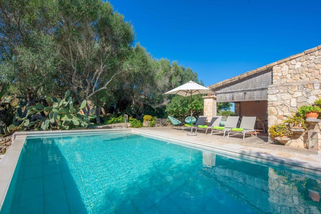 a swimming pool in a yard with chairs and an umbrella at Son Poca Palla in Sant Llorenç des Cardassar