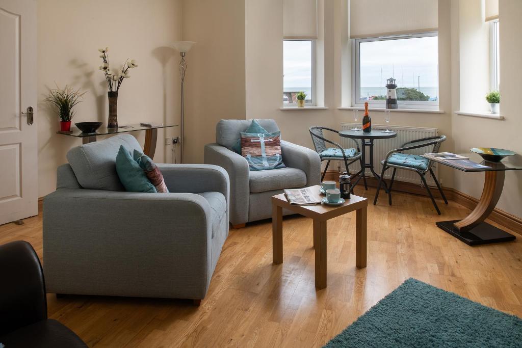 uma sala de estar com um sofá, cadeiras e uma mesa em Puffin View em Llanfairfechan
