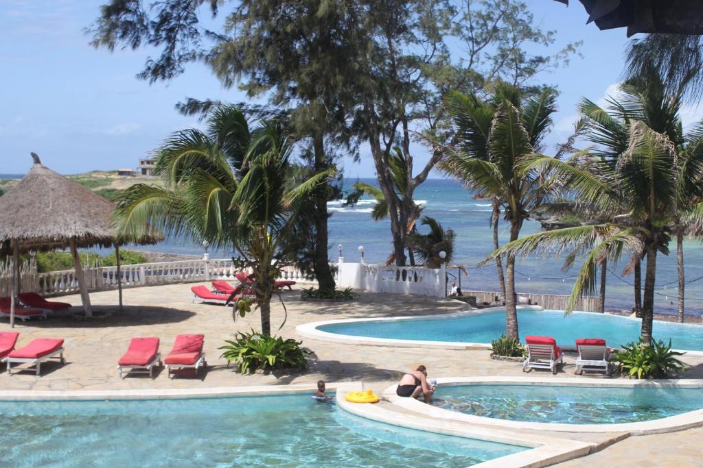 a pool at a resort with the ocean in the background at Lily Palm Resort in Watamu