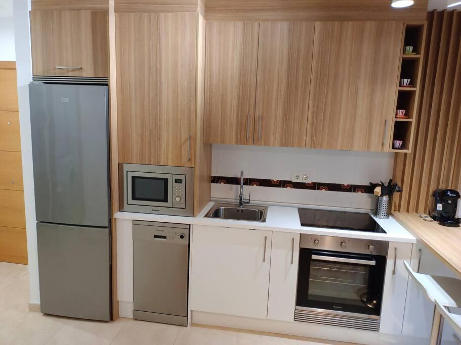 eine Küche mit weißen Geräten und Holzschränken in der Unterkunft Apartamento Playa de Coroso in Ribeira