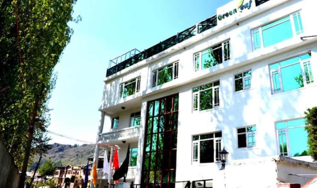 een wit gebouw met vlaggen ervoor bij Hotel Green Leaf , Srinagar in Srinagar