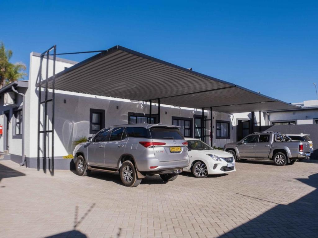 two cars parked in a parking lot in front of a building at The Lofts Prestige Suites in Windhoek