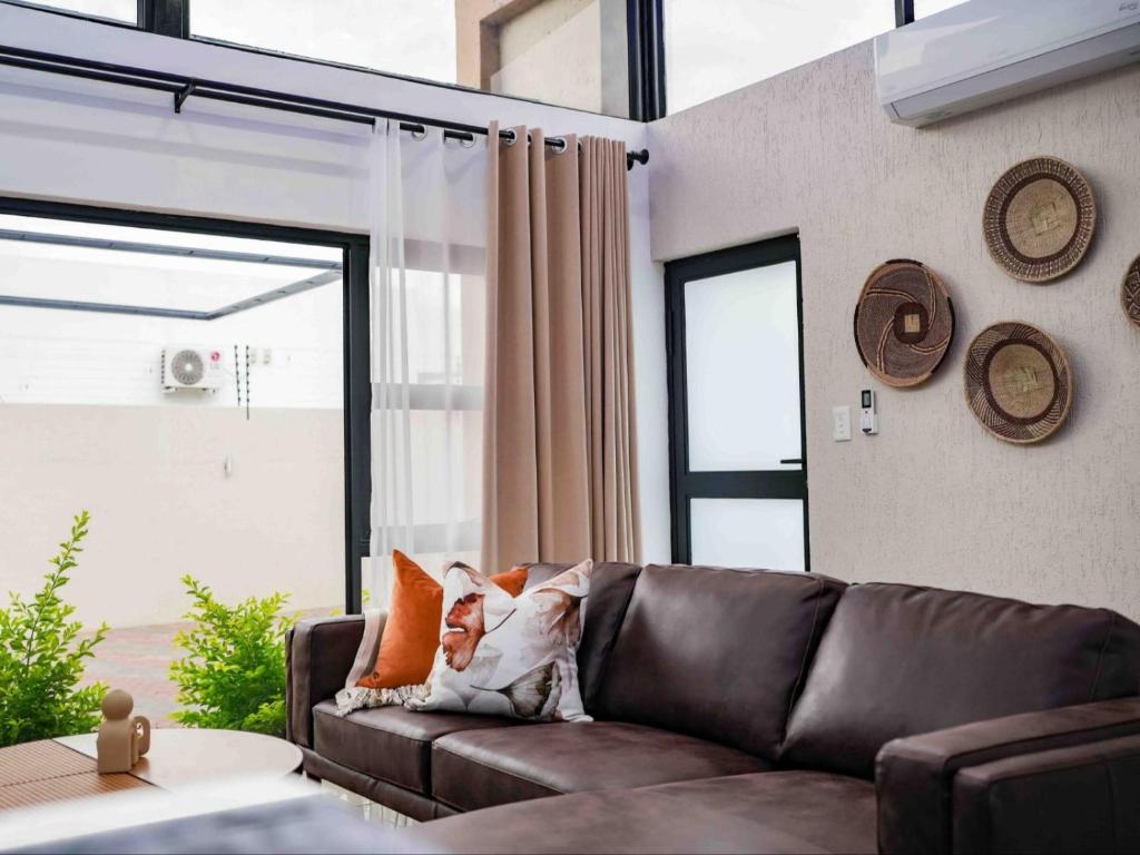 a living room with a brown couch and a window at The Lofts Prestige Suites in Windhoek