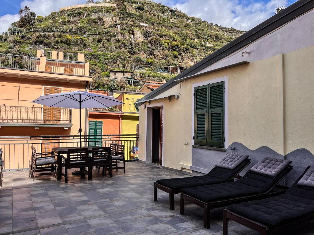 une terrasse avec une table, des chaises et un parasol dans l'établissement Luxury Apartment Manarola by Arbaspàa, à Manarola