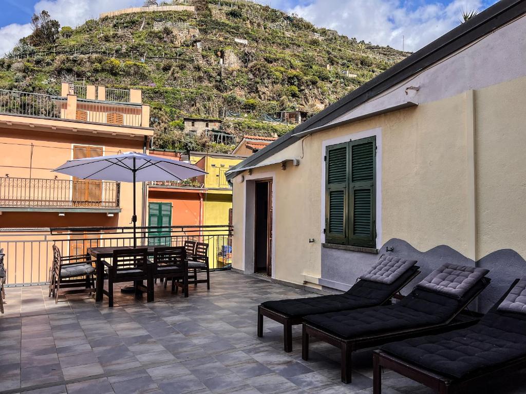 a patio with a table and chairs and an umbrella at Luxury Apartment Manarola by Arbaspàa in Manarola