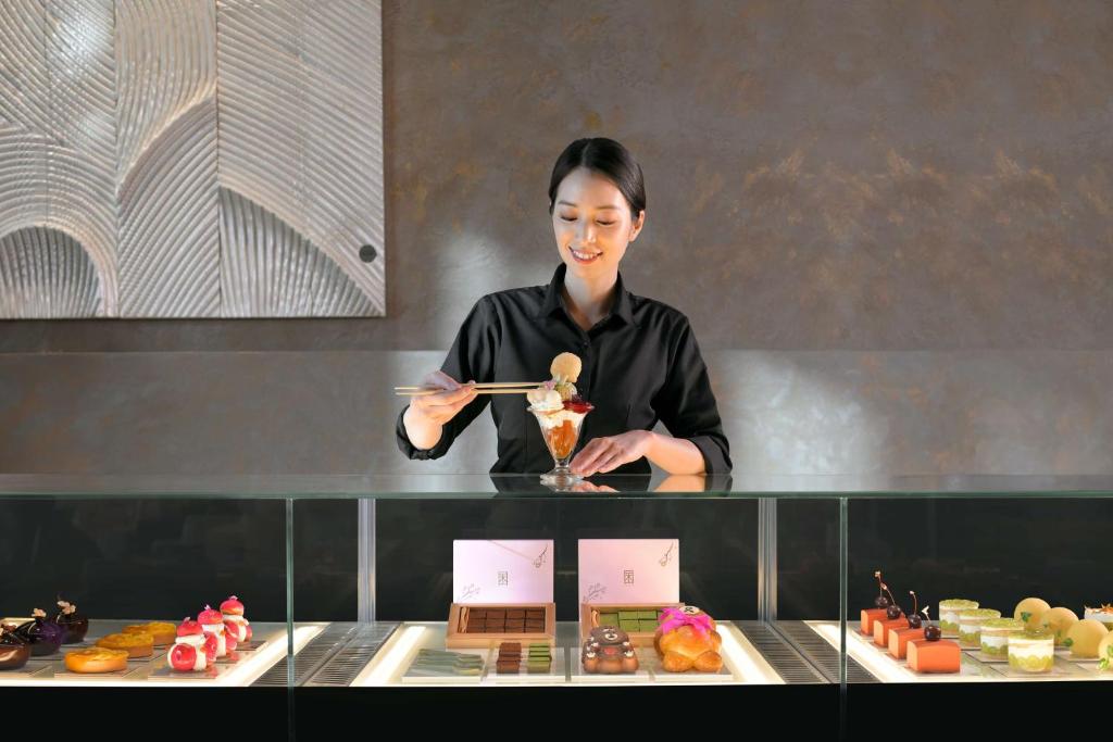 a woman is standing behind a counter with food at Banyan Tree Dubai at Bluewaters in Dubai