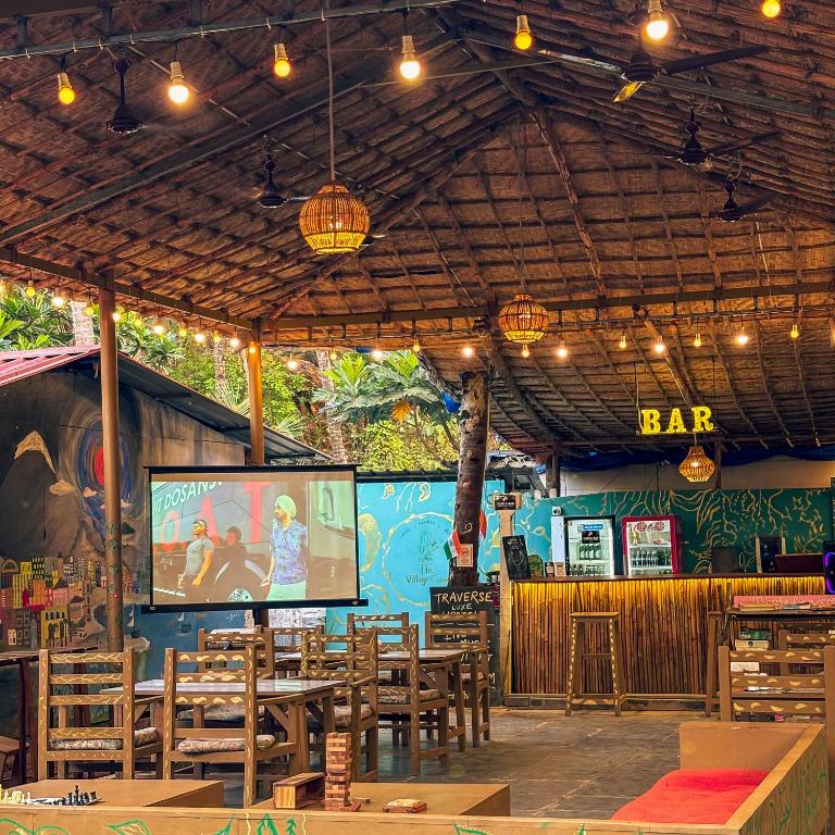 a restaurant with tables and chairs and a bar at Traverse Luxe Hostel Palolem in Palolem