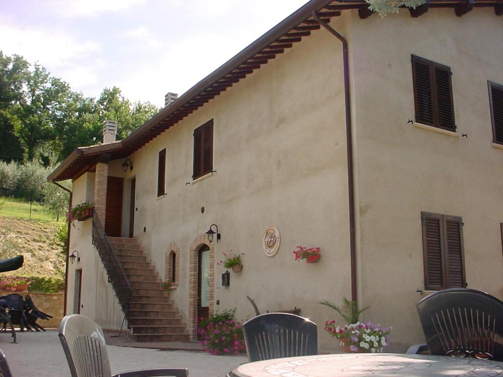 um edifício com uma mesa e cadeiras em frente em Agriturismo La Cantina San Martino em Assisi