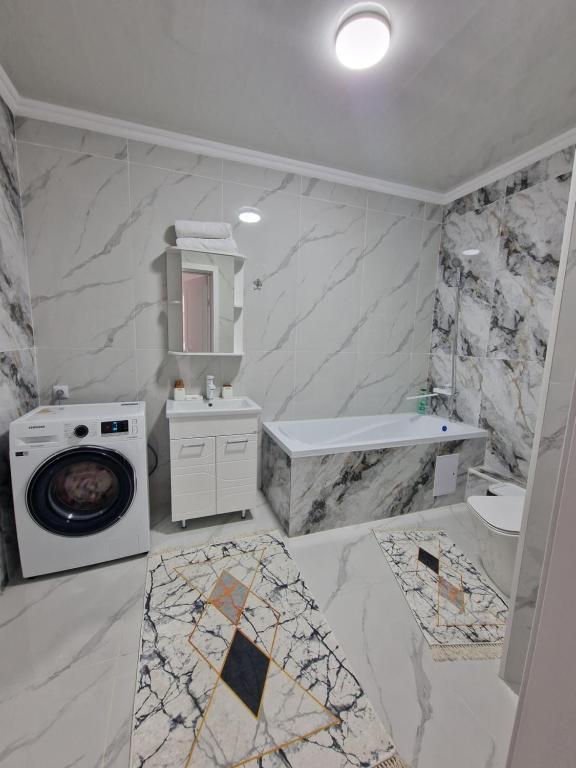 a white bathroom with a washing machine and a sink at Jetysu2 in Prigorodnyy