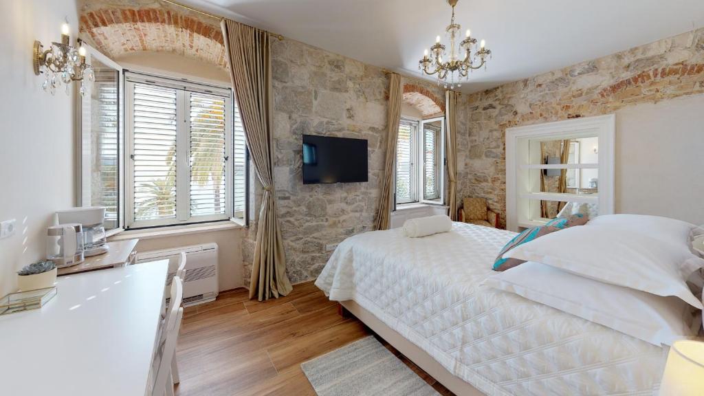 a bedroom with a white bed and a tv on the wall at Chrysanta Apartments in Split