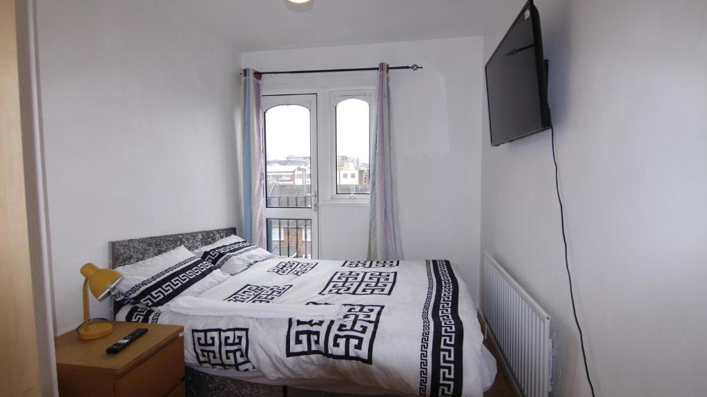 a bedroom with a bed and a tv and a window at 3BED Maisonette Near CityCentre in Birmingham