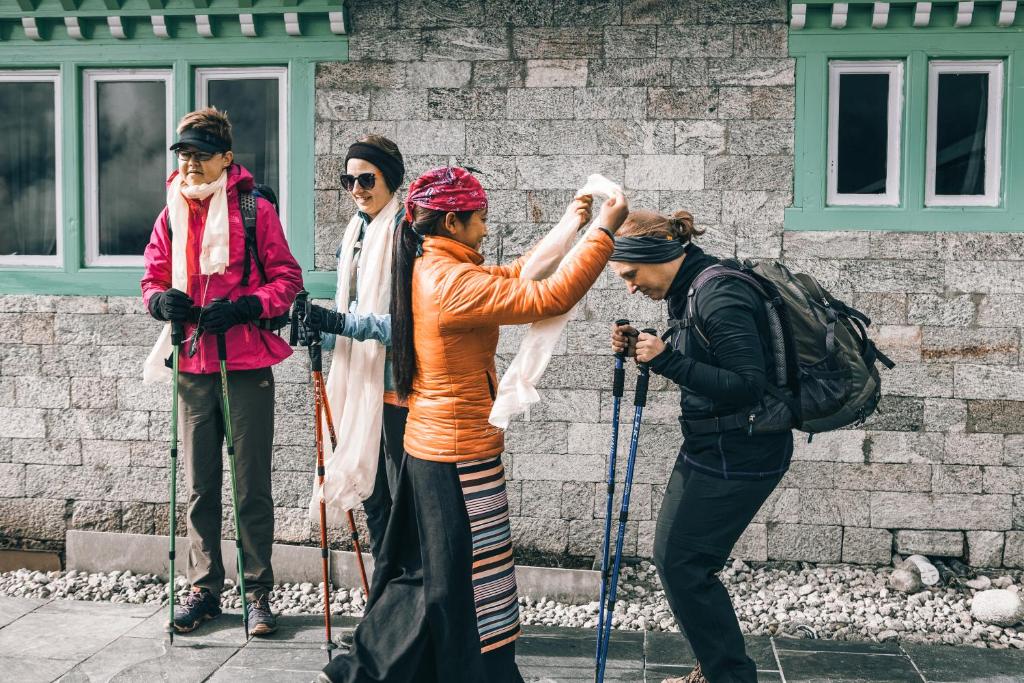 Namche的住宿－Mountain Lodges of Nepal - Namche，一群三人在滑雪板上,在一座建筑前