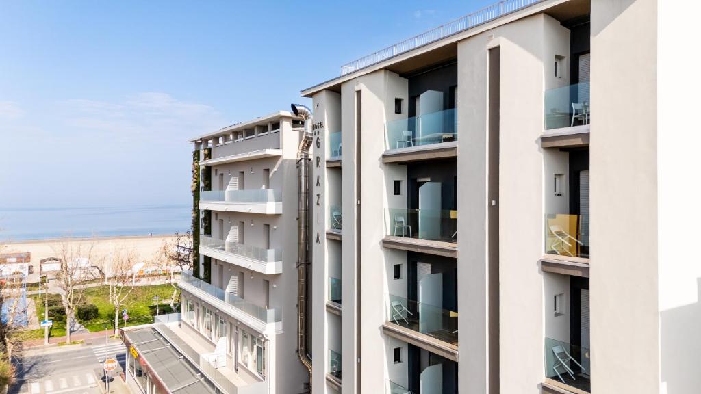 un edificio de apartamentos con balcones y el océano en el fondo en Hotel Grazia Riccione, en Riccione