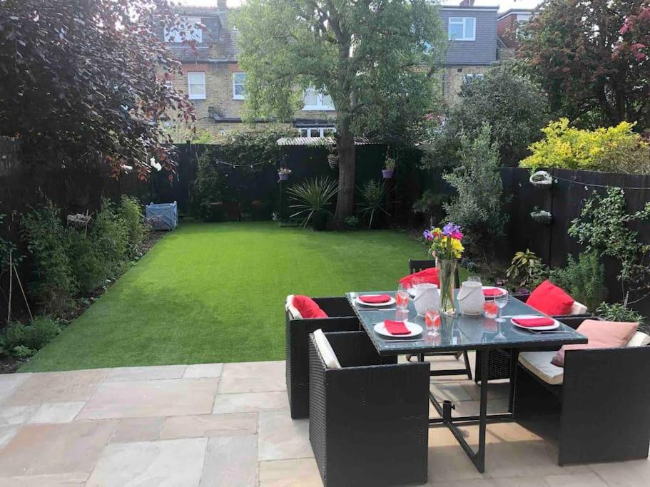 d'un jardin avec une table, des chaises et une pelouse. dans l'établissement Luxury 4 bedroom house in London featured on TV, à Londres