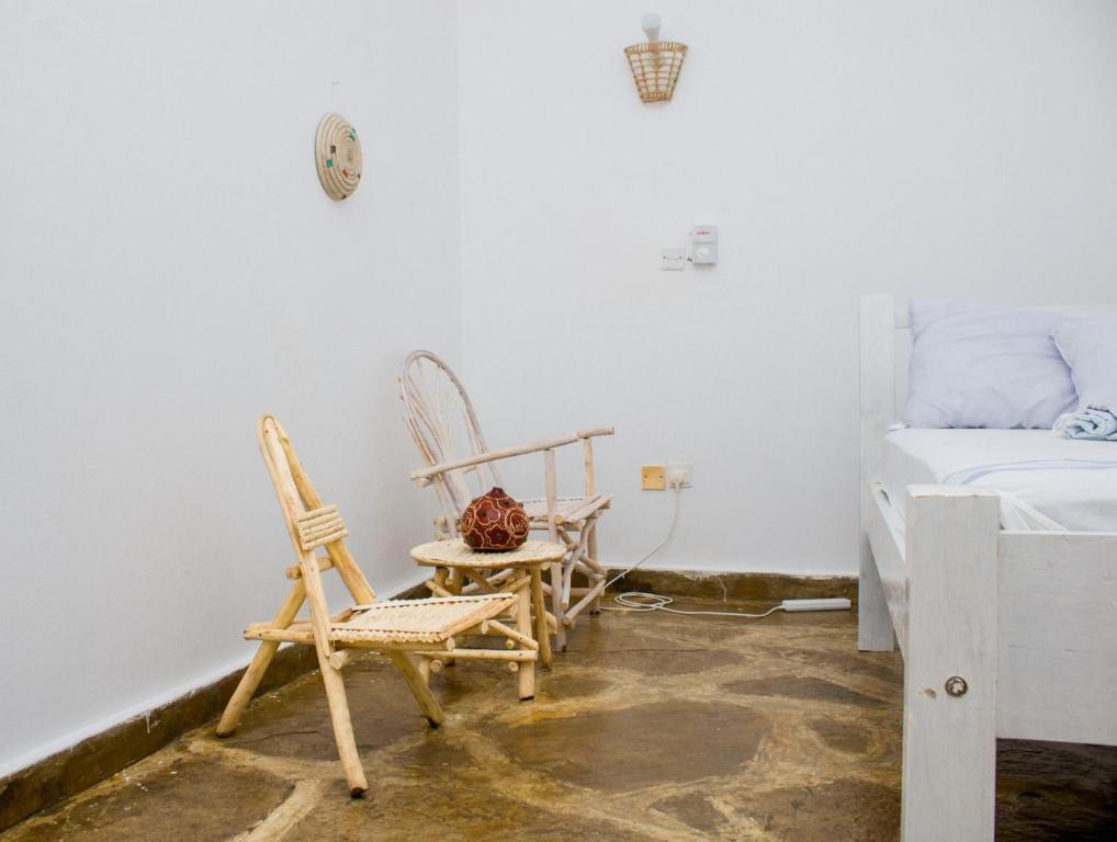 2 sillas y una mesa en una habitación con cama en 3 bedroom white house malindi en Malindi