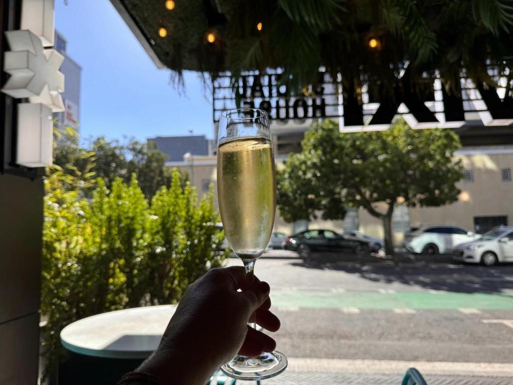a person holding up a glass of champagne at Bree Street Apartment - Explore, Eat, Experience Cape Town in Cape Town