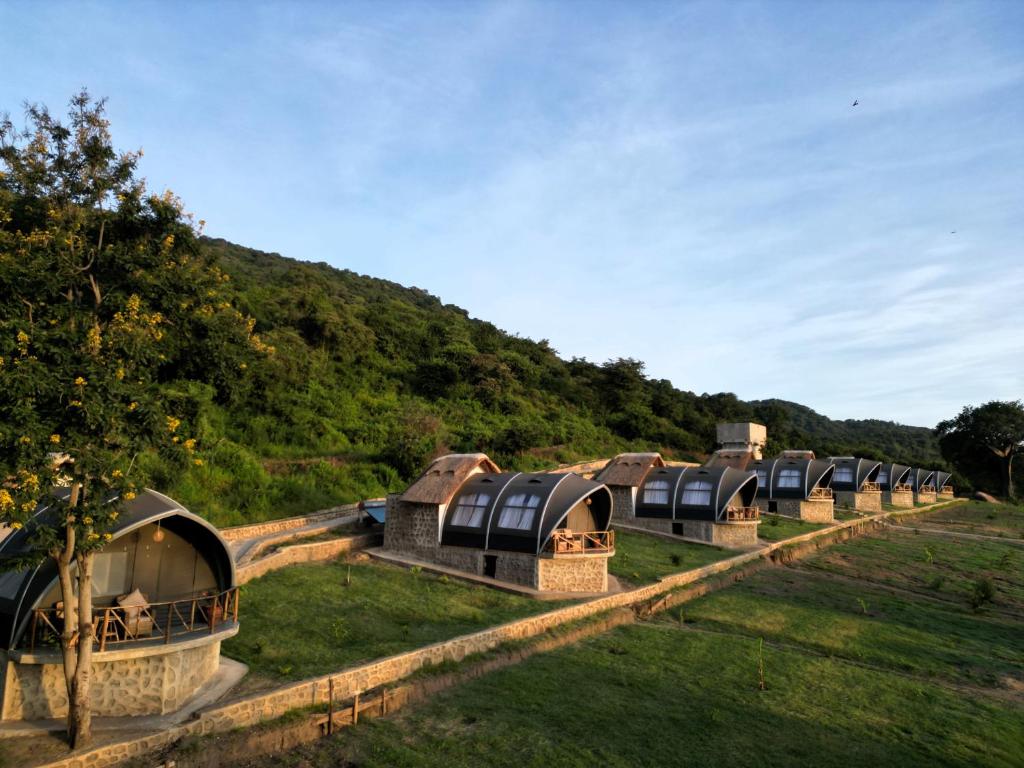 a row of domes in a field with a mountain at Africa Safari Rift Valley in Magara